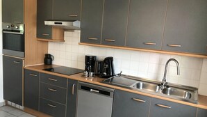 A modern kitchen with dark cabinets, a built-in oven, a coffee maker, and a dishwasher. - Cozy Vacation Home for 8 Persons in Heers (Heers)