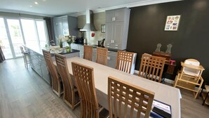 Une cuisine moderne avec des meubles gris, un îlot central doté d’un évier et des chaises en bois disposées autour d’une table à manger.