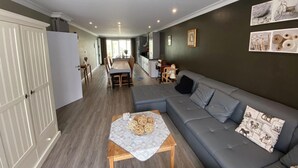 Un salon moderne avec un canapé gris, une table basse en bois et un coin repas comprenant une table et des chaises.
