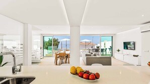 A modern kitchen with a central island, a dining area with a view, and a living space with a TV.