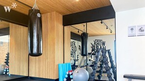 Une salle de sport équipée d’un sac de frappe, de ballons d’exercice, d’haltères et d’un banc.