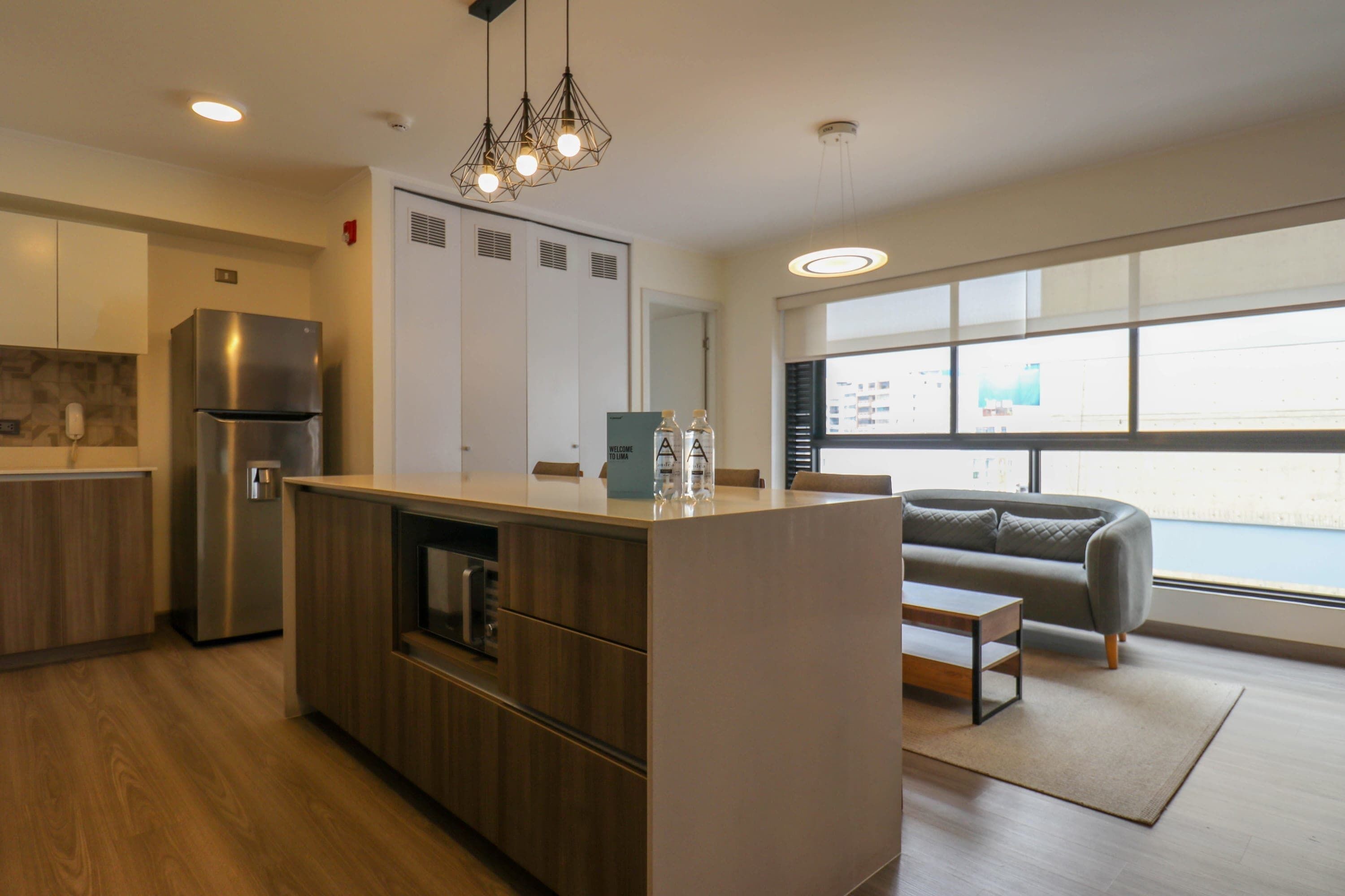 A modern kitchen with a central island, stainless steel appliances, and a large window providing a view of the city.