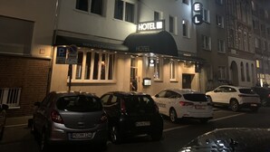 A hotel with a prominent "HOTEL" sign, multiple floors, and parked cars in front.