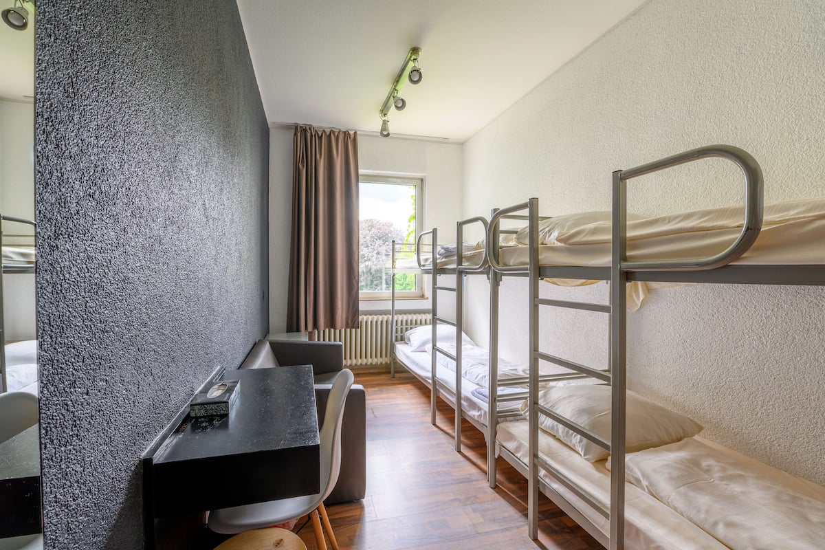 Een slaapzaal met stapelbedden, een bureau en een stoel.