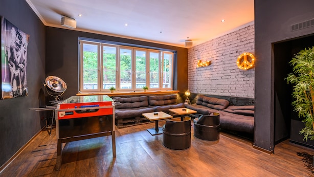 A modern lounge with a foosball table, a large window, a brick wall, and a cozy seating area.