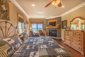 A bedroom with a large bed, a fireplace, a dresser, and a ceiling fan. - Heaven South-Mountain Views - Hot Tub - Fire Pit -Secluded -4WD-AWD (Bryson City)