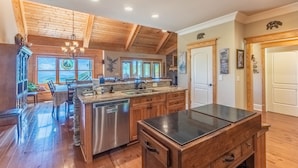 A spacious kitchen with wooden beams, a central island, and a dishwasher. - Heaven South-Mountain Views - Hot Tub - Fire Pit -Secluded (Bryson City)