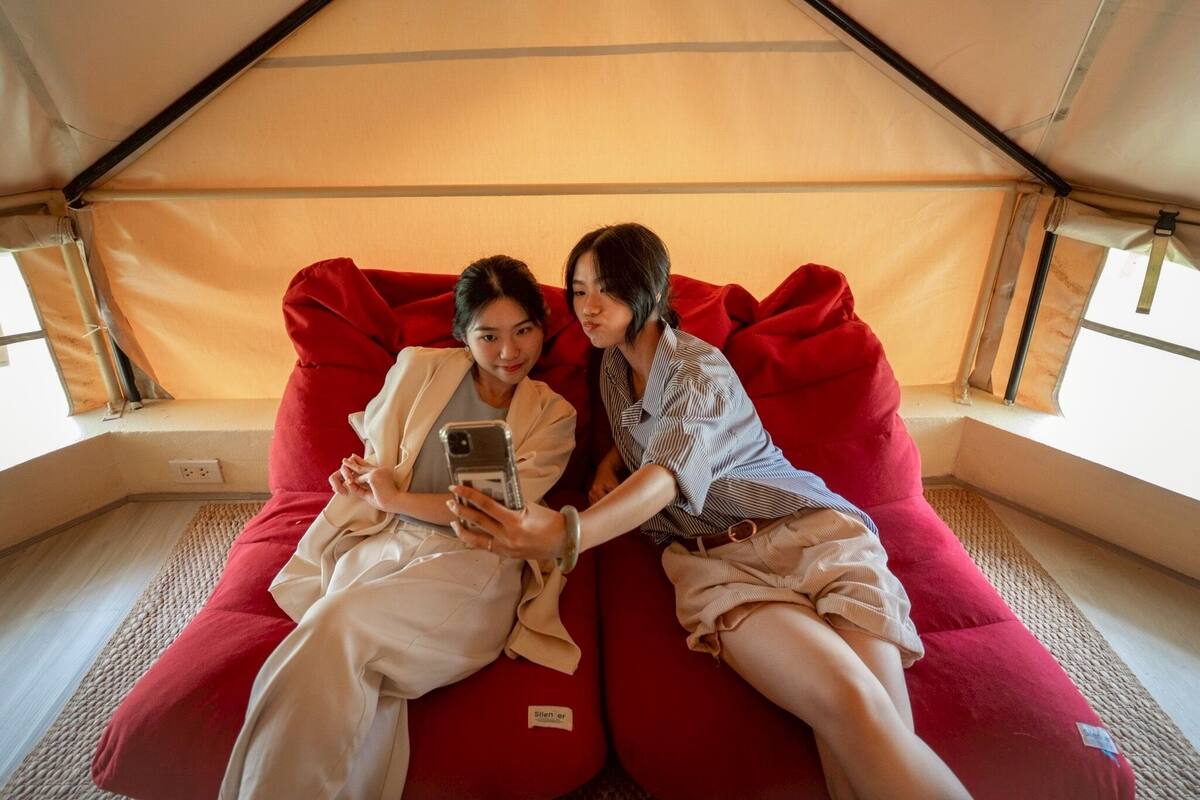 Two people sitting on a red couch inside a tent-like structure.