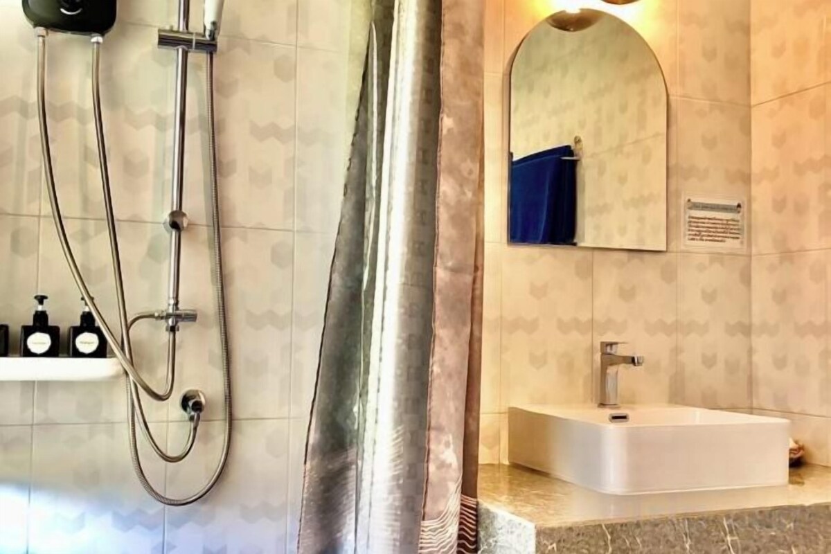A bathroom with a shower, a sink, and a mirror.