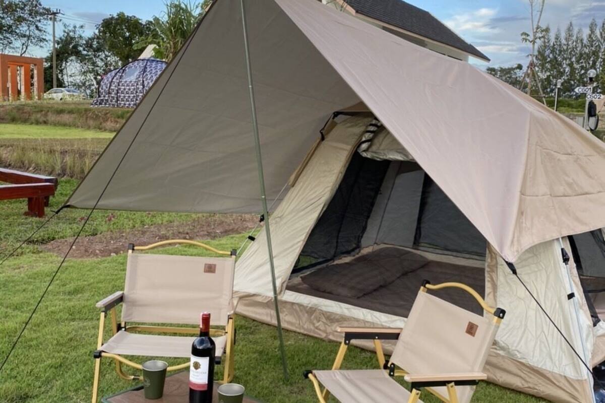 A camping setup with a tent, two chairs, a table, and a crate.