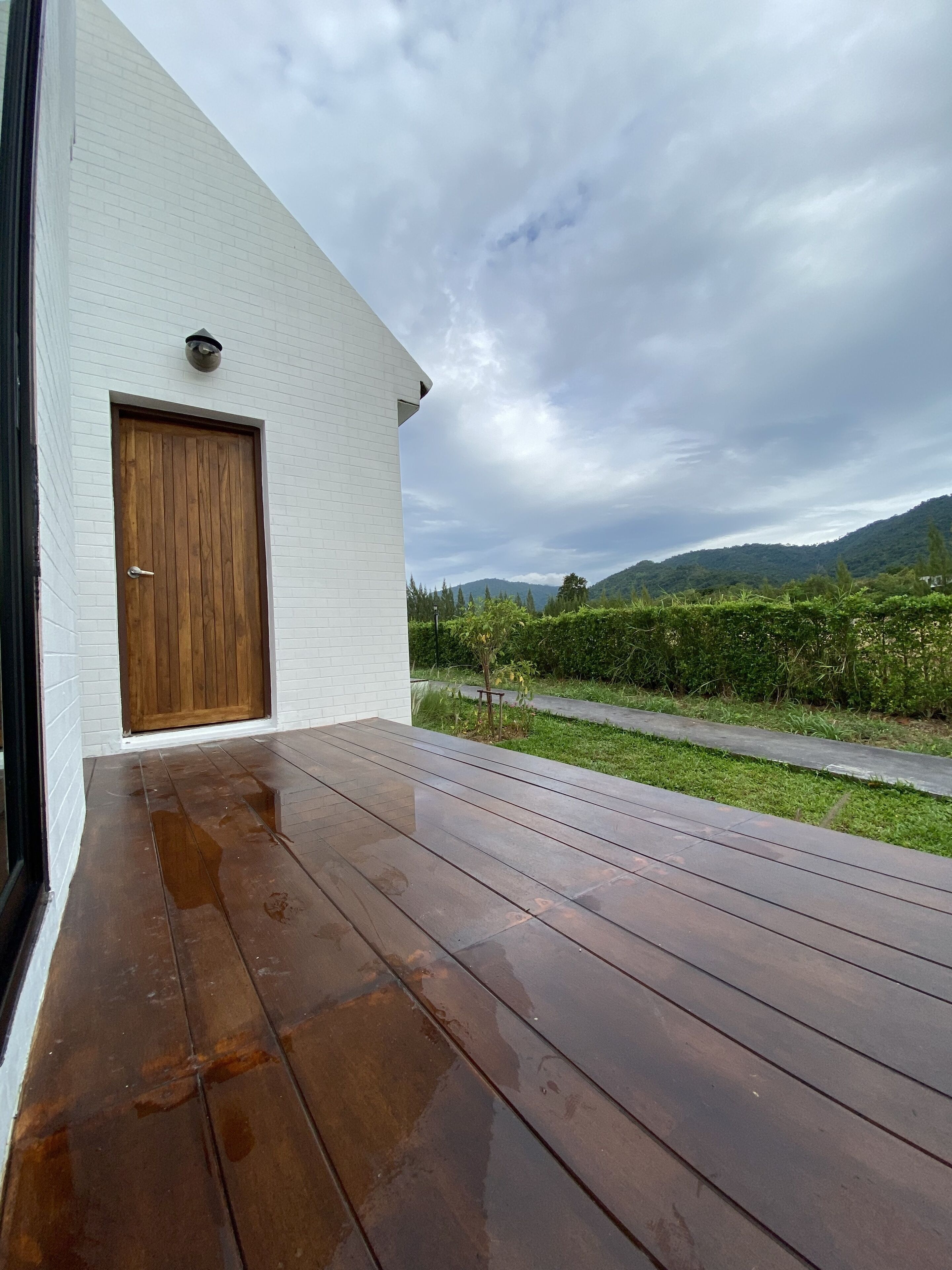 A modern building with a wooden door and a wet wooden deck.