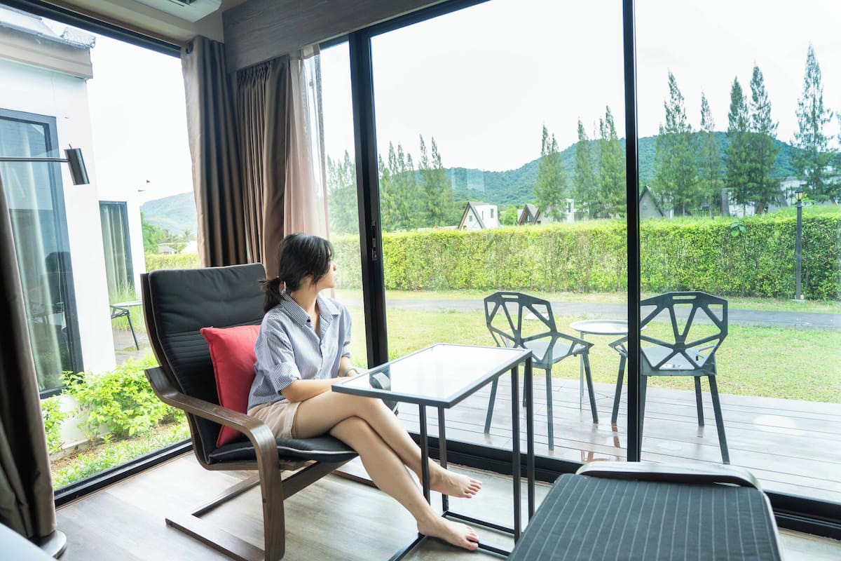 A modern room with a large window, a comfortable chair, a small table, and a bench.