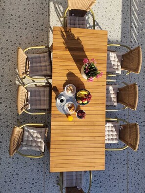 A wooden table with six wicker chairs, a vase of flowers, and a bowl of fruit. - Large House with a Pool (La Victoria)