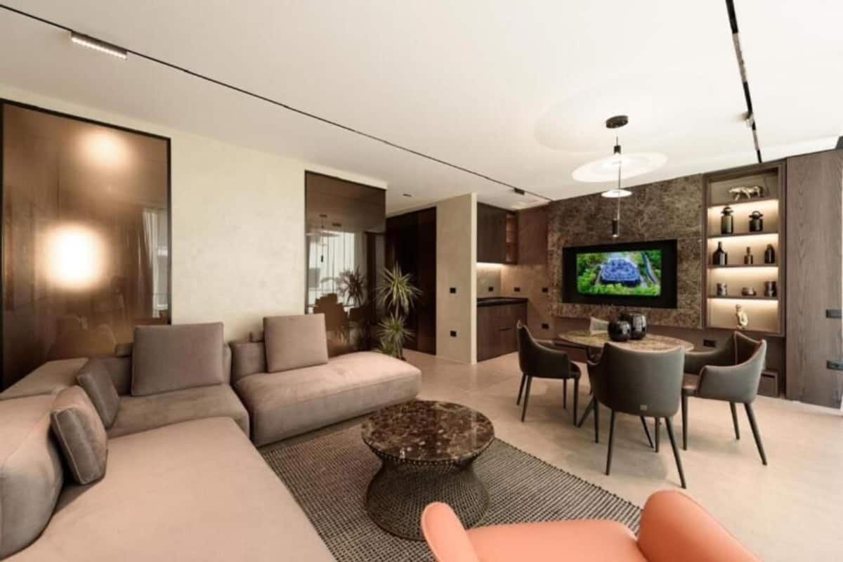 Uma sala de estar moderna com um sofá seccional, uma mesa de centro redonda e uma televisão.