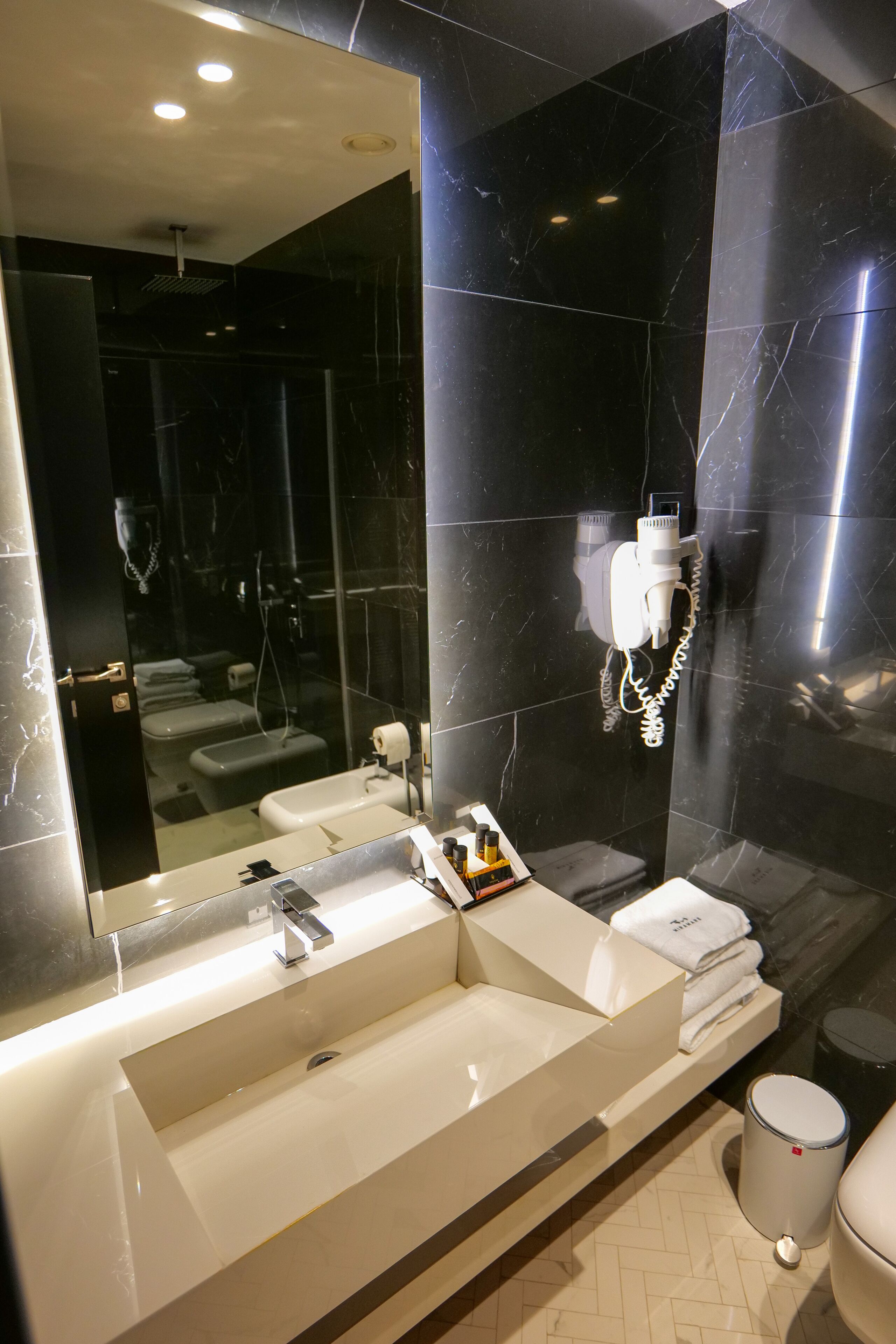 Un baño moderno con un espejo grande, lavamanos dobles y un perchero para toallas.