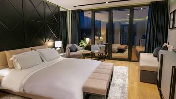 Quarto de hotel moderno com uma cama grande, uma escrivaninha, uma cadeira e um sofá.