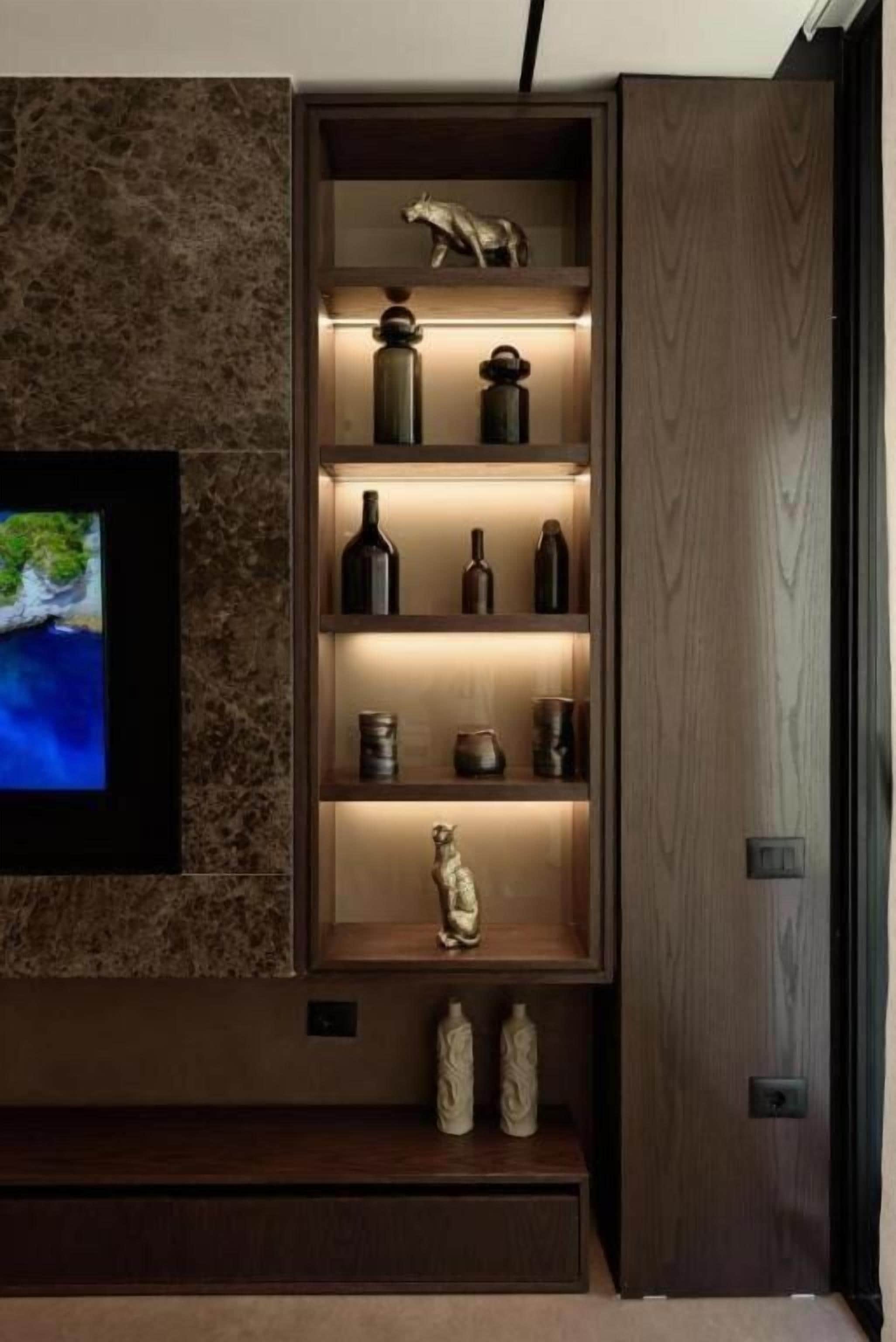 A wooden cabinet with shelves containing various decorative items and a television mounted on the wall.