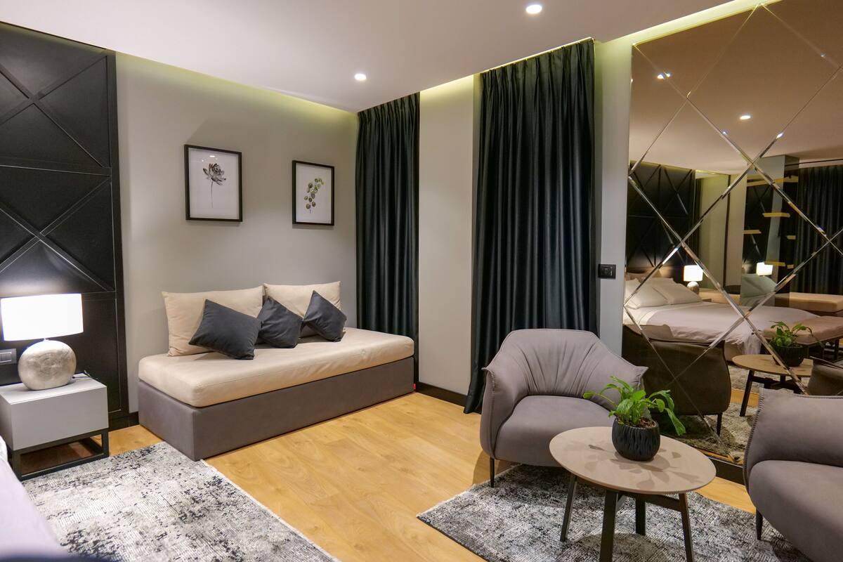 Uma sala de estar moderna com um sofá, poltronas, uma mesa de centro e uma cama.