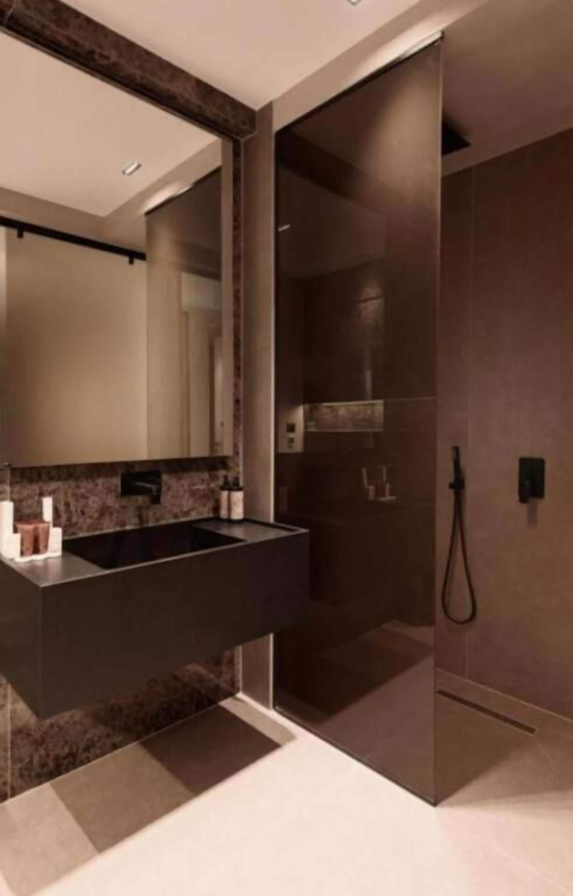 A modern bathroom with a large mirror, a dark countertop, and a shower area.