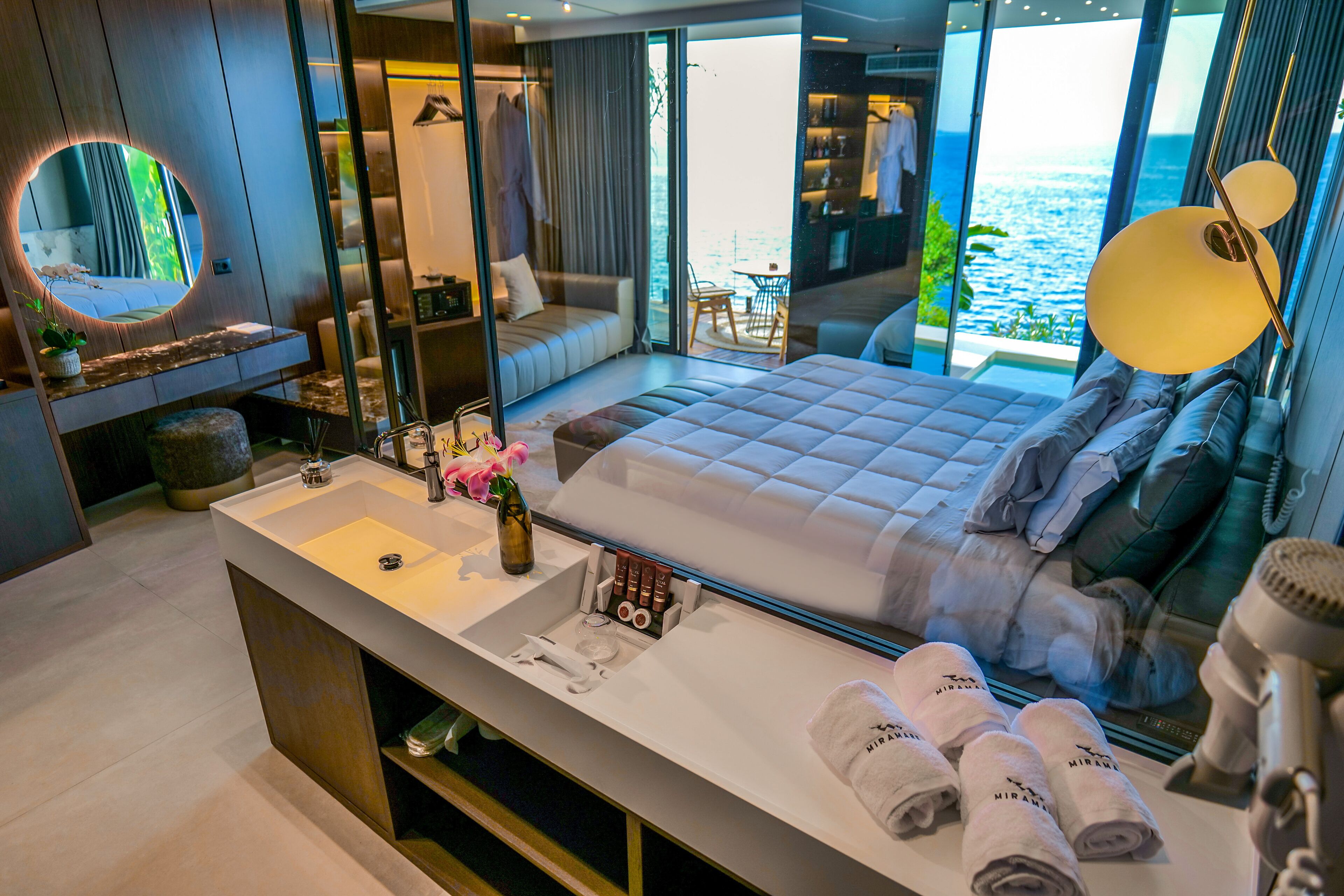 Una camera moderna con un letto grande, una toeletta con specchio e vista sul mare.