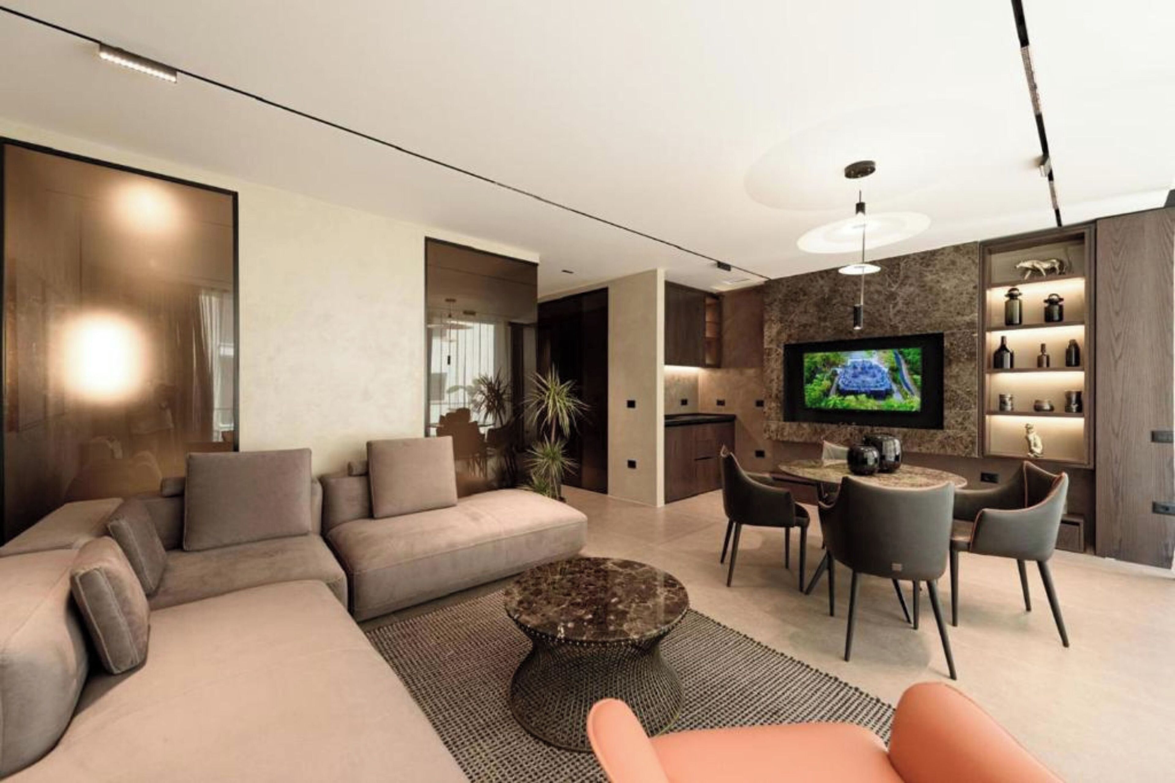A modern living room with a sectional sofa, a round coffee table, and a TV mounted on the wall.