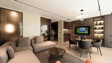A modern living room with a sectional sofa, a round coffee table, and a TV mounted on the wall.