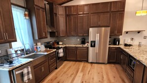 A modern kitchen with wooden cabinets, stainless steel appliances, and a granite countertop.