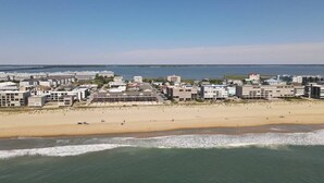 A coastal cityscape with a wide beach, buildings along the shore, and a clear view of the ocean.