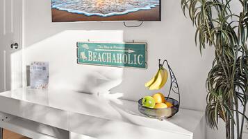 Een witte receptiebalie met een bord in strandthema, een fruitmand en een hangplant.