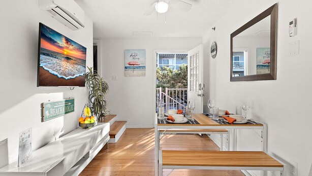 A hallway with a wooden bench, a dining table set for two, and a view of the outside balcony.