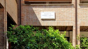 Une plaque sur un bâtiment en briques portant l’inscription : « PIAZZETTA ROMOLO VASELLI, CHEVALIERS DU TRAVAIL, PROPRIÉTÉ PRIVÉE ».