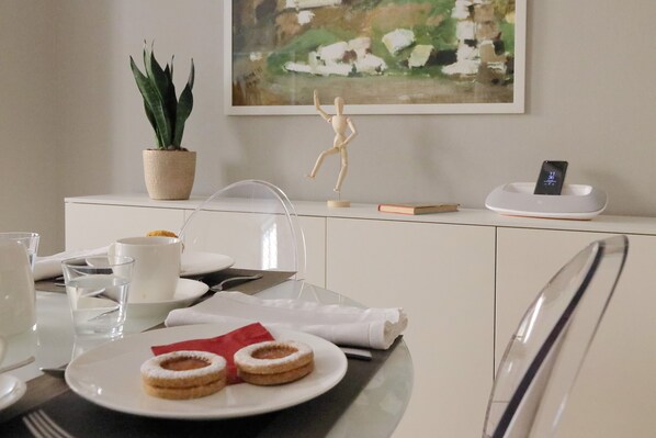A dining table with plates of food, a potted plant, a wooden sculpture, and a smartphone charging station.