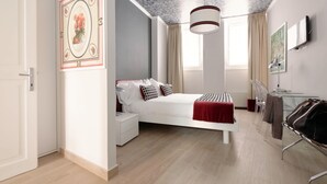 Un dormitorio moderno con cama, mesita de noche y escritorio con sillas.