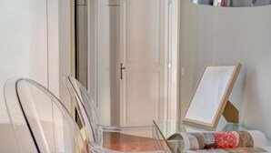 A dining area with a glass table, clear chairs, and a framed picture on the wall. - Piazzetta Margutta - A3 (Rome)