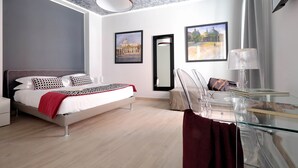 A modern bedroom with a bed, a glass table, and two framed pictures on the wall. - Piazzetta Margutta - A12 (Rome)