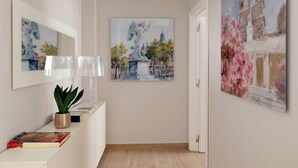A hallway with a white console table, a potted plant, and two framed paintings depicting architectural scenes. - Piazzetta Margutta - A12 (Rome)