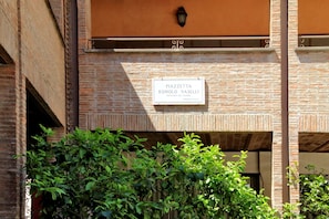 Segnaletica con la scritta 'PIAZZETTA ROMOLO VASELLI' su un edificio in mattoni.