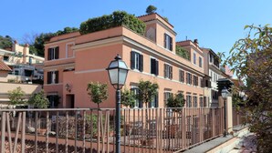Un edificio a più piani con una facciata rosa, un cortile recintato e un lampione.