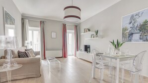 En moderne stue med en sofa, et glasbord og et spiseområde med et bord og stole i glas.