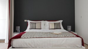 A neatly made bed with a patterned bedspread, two pillows, and a book on the bed.