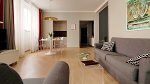 A modern living room with a grey sofa, a coffee table, and a dining area with a white table and chairs. - Piazzetta Margutta - T1 (Rome)