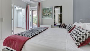 Een moderne slaapkamer met een groot bed, een rode plaid, decoratieve kussens, een spiegel en uitzicht op de omgeving.