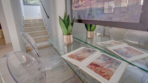 A modern dining area with clear glass tables and chairs, a staircase, and a large framed painting on the wall. - Piazzetta Margutta - A1 (Rome)