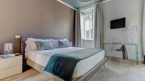 A modern bedroom with a bed, bedside table, lamp, TV, and a glass desk with a chair. - Piazzetta Margutta - A1 (Rome)