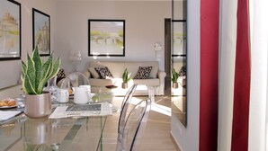 A modern living room with a glass dining table, clear chairs, a sofa, and a potted plant. - Piazzetta Margutta - B6 (Rome)