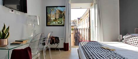A hotel room with a bed, a desk with a lamp, a chair, a TV mounted on the wall, and a painting.