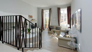 Ein geräumiger Wohnbereich mit Treppe, einer Sofagarnitur, einem Couchtisch und einem Fernseher.