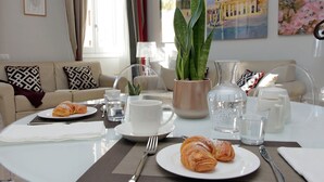 Ein Essbereich mit gedecktem Tisch für das Frühstück, inklusive Croissants, einer Tasse und einer Karaffe.