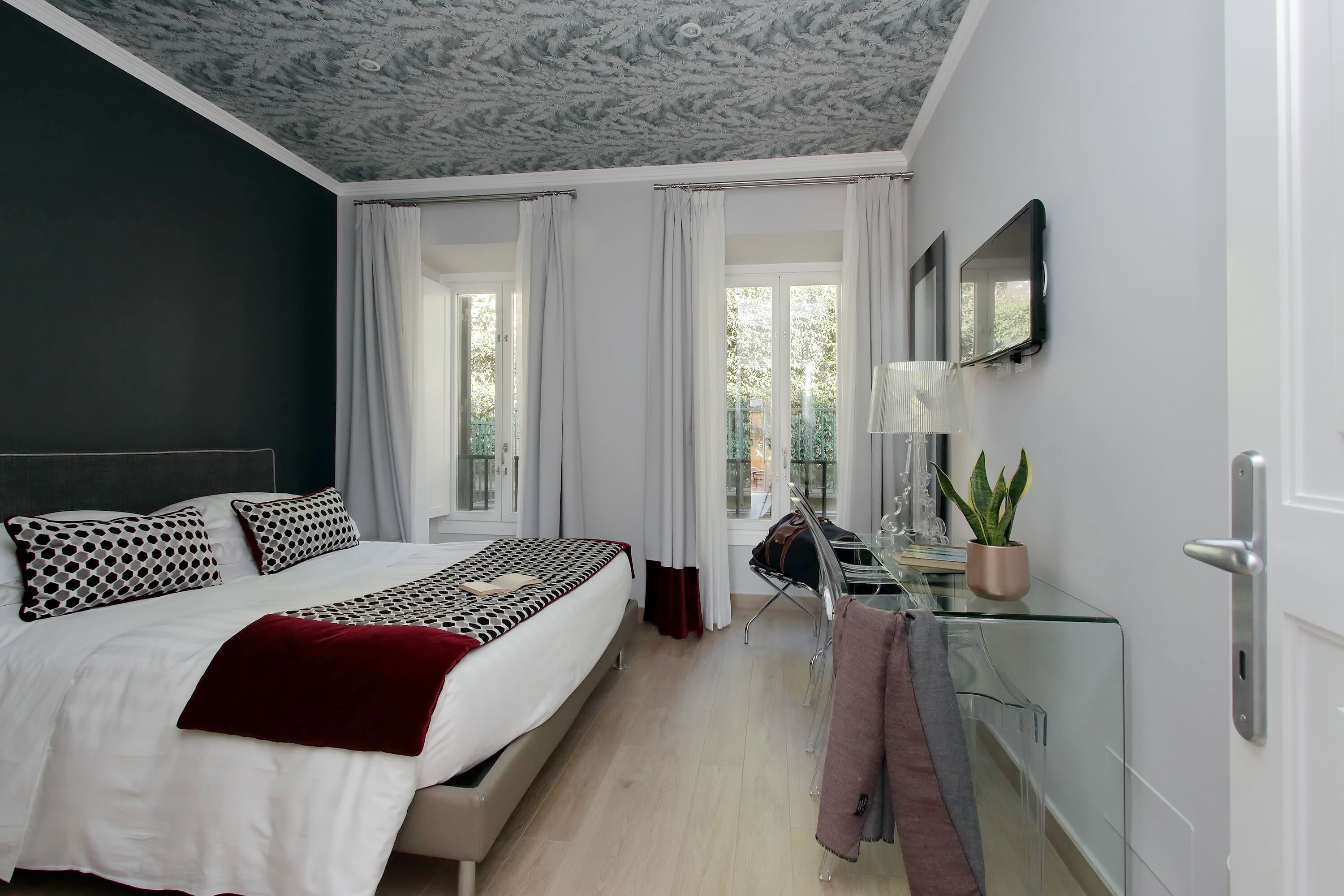 Un dormitorio moderno con una cama, un escritorio, una silla y una planta en maceta.