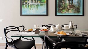 Una mesa de comedor con platos de comida, tazas y cubiertos, rodeada de sillas negras.